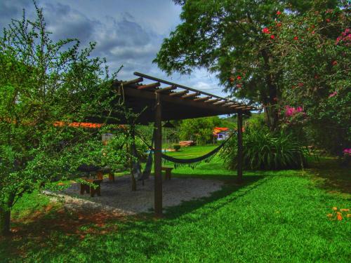 a hammock under a wooden pergola in a park at Pousada Mandalla in Serra do Cipo