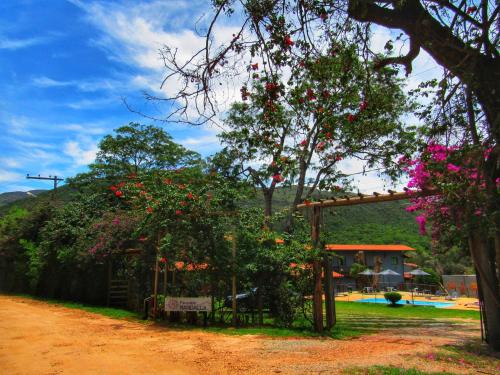 a garden with red flowers on trees and a house at Pousada Mandalla in Serra do Cipo
