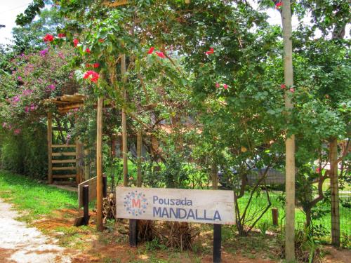 a sign in front of a tree with flowers at Pousada Mandalla in Serra do Cipo