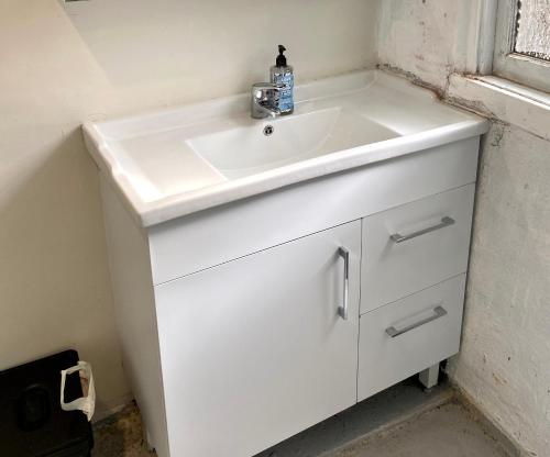 a white sink in a bathroom with a window at Coco’s Abode in Sydney