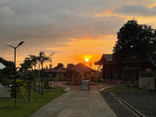 a sunset over a building with the sun setting at White Hut Villas by Asog resort in Naga