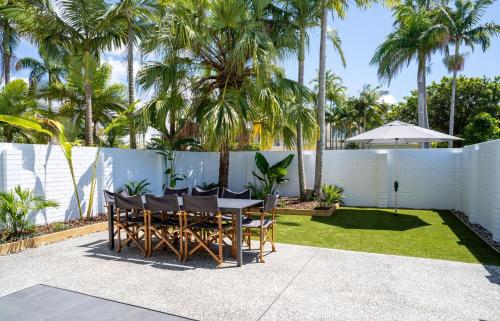 a patio with a table and chairs and palm trees at The Oasis has a private courtyard and ideal location to walk in Noosa Heads