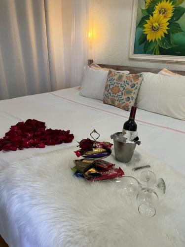 a white bed with roses and a bottle of wine on it at Chalés na Roça in Pirenópolis