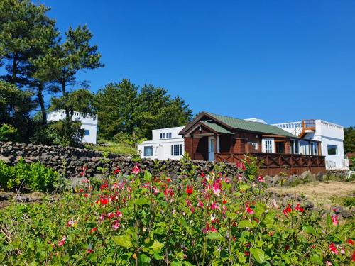 a house on a hill with flowers in the foreground at Jeju Damda in Jeju