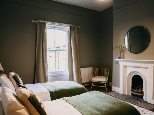 a bedroom with two beds and a window and a fireplace at No 1 Pepper Arden in Northallerton