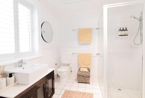 a white bathroom with a toilet and a shower at 70 On Mortimer in Mudgee