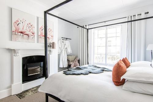 a white bedroom with a bed and a fireplace at 70 On Mortimer in Mudgee