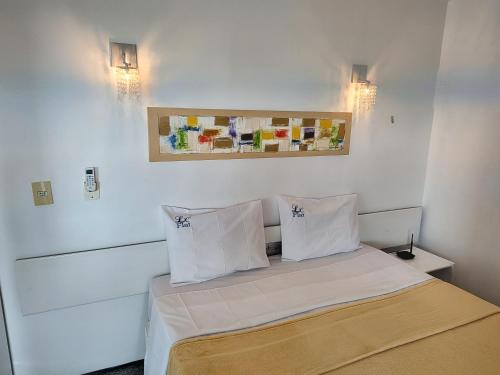 um quarto com uma cama com lençóis brancos e almofadas em Belíssimo frente mar 107 em Fortaleza