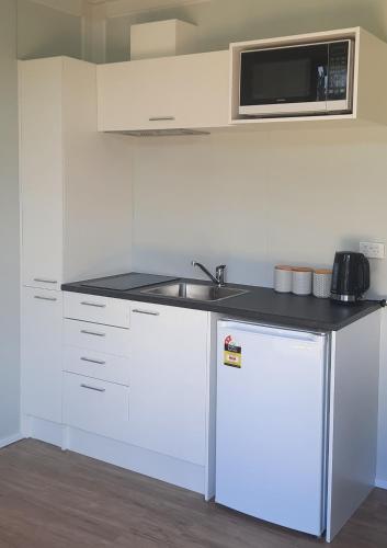a white kitchen with a sink and a microwave at The Morgans in Waiau