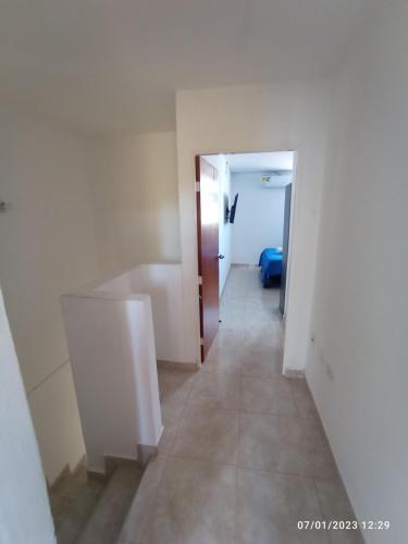 um corredor que leva a um quarto com paredes brancas e pisos em azulejo em Habitación doble cómoda em Valledupar