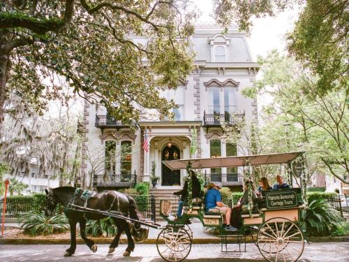 a horse drawn carriage in front of a house at Southern Charmer-Historic District Downtown-Front Porch-Walk Score 90!!- FREE Private Parking-1 Min Walk to Forsyth Park in Savannah