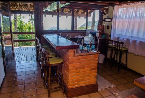 a bar in a restaurant with chairs and windows at Chalé vista exuberante na Serrinha do Alambari in Resende