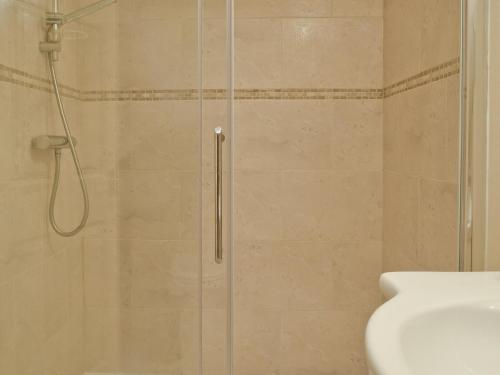 una ducha con una puerta de cristal junto a un lavabo en Sunrise en Coughton