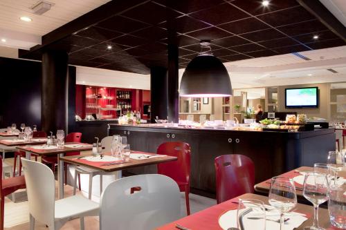 タッサン・ラ・ドゥミ・リュンヌにあるカンパニール リヨン ウエスト タッシンのテーブルと椅子のあるレストラン、バー