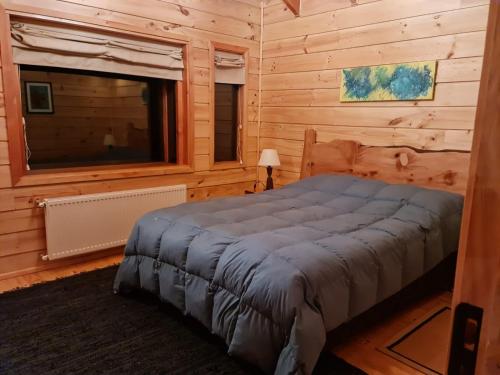 1 dormitorio con 1 cama en una cabaña de madera en HuiloHuilo San Avellano en Reserva Biologica, en Reserva Biológica Huilo Huilo