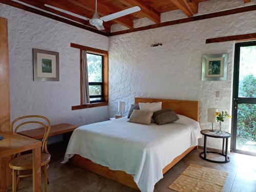 a bedroom with a bed and a table and two windows at Canto de Aves in Malinalco