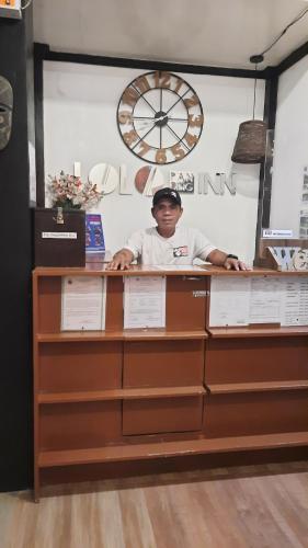 a man standing behind a counter with a clock at Lolo Panding Inn in El Nido