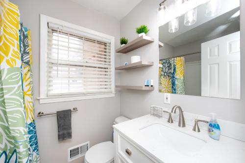 a bathroom with a sink and a toilet and a mirror at Roomy 3BR 2 Bath minutes to Uptown and Airport Ideal for small families in Charlotte