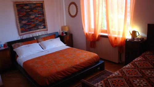 a bedroom with a bed and a window with curtains at Il Melograno in Borgo San Dalmazzo