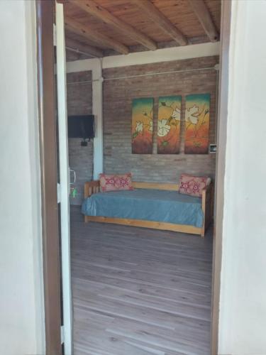 1 dormitorio con 1 cama y pinturas en la pared en Las Violetas en San Rafael