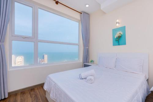a bedroom with a white bed with a large window at John Wick 2 Apartment in Vung Tau in Vung Tau
