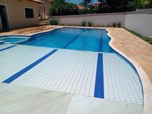 a swimming pool with blue tiles on the floor and a house at Chácara/ Rancho Família Campos in Bicanca