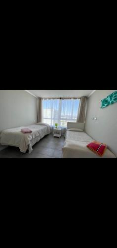a bedroom with two beds and a window at II Cerca de la playa y del centro in La Serena