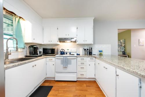 a white kitchen with white cabinets and a wooden floor at Roomy 3BR 2 Bath minutes to Uptown and Airport Ideal for small families in Charlotte
