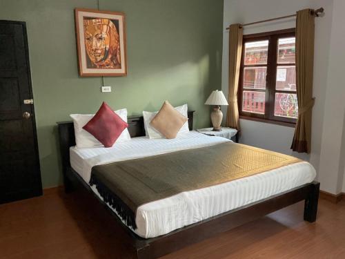 a bedroom with a large bed with red and white pillows at Baan Klang Vieng in Chiang Mai