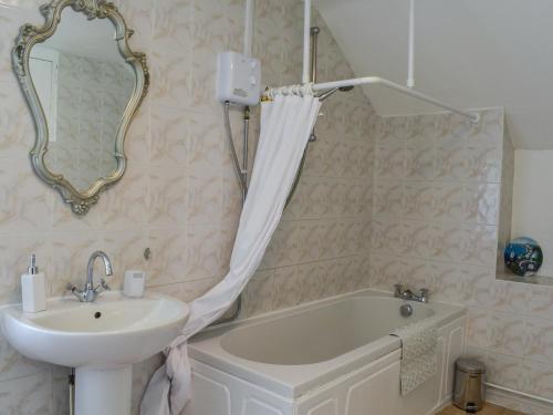 ein Badezimmer mit einem Waschbecken, einer Badewanne und einem Spiegel in der Unterkunft Bron Berllan in Llandudno
