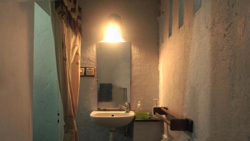 a bathroom with a sink and a light on the wall at Budarno Homestay in Yogyakarta