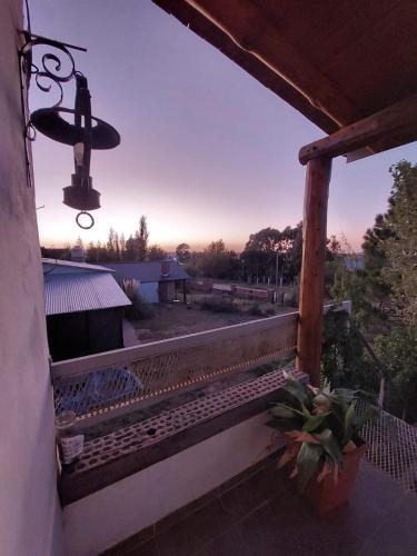 un banco en un porche con una puesta de sol en el fondo en Terrazas del Río en Achiras