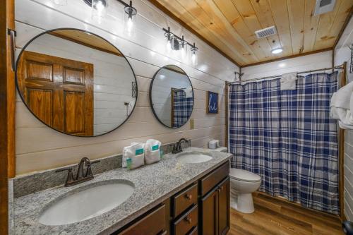 a bathroom with two sinks and a toilet and mirrors at Osprey Nest Cottage Modern New Cabin in Pigeon Forge