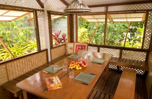 una sala da pranzo con tavolo in legno e alcune finestre di Te Ora Hau Ecolodge ad Afareaitu