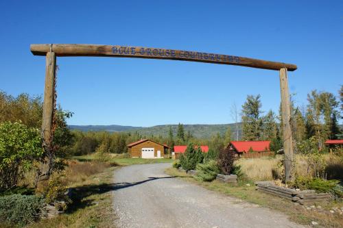 a wooden arch over a dirt road with a house in the background at Blue Grouse Country Inn B&B in Clearwater