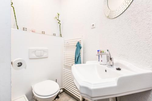 a white bathroom with a sink and a toilet at Apartment Cologne in Cologne