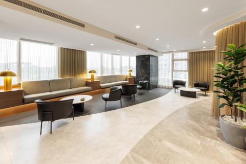 a lobby with a couch and chairs and tables at Meriton Suites George Street, Parramatta in Sydney