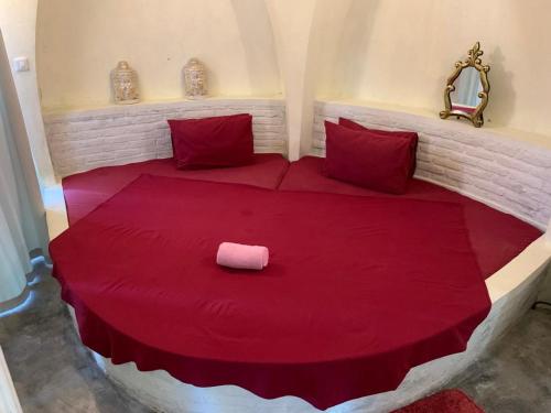 Una cama con sábanas rojas y una almohada rosa. en Villa Kingdome - 1 Bedroom, en Teluknarat