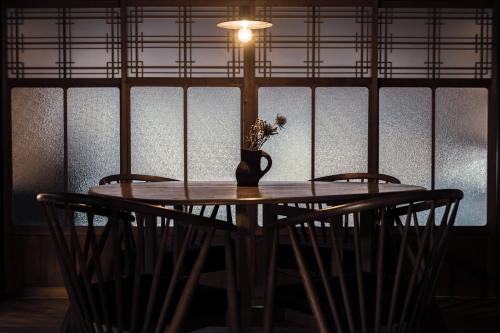 a table with chairs and a vase with flowers on it at taos 丹波の風土を感じられる一棟貸切の宿 in Sasayama