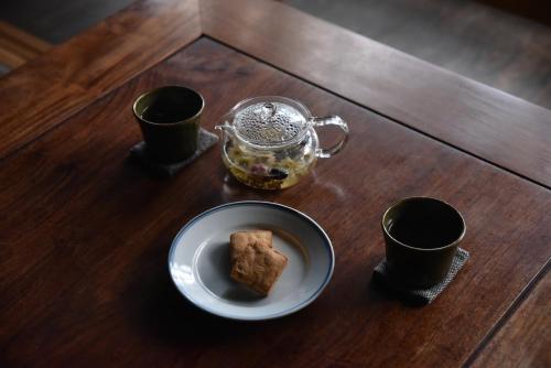 a table with a plate of food and two cups at taos 丹波の風土を感じられる一棟貸切の宿 in Sasayama