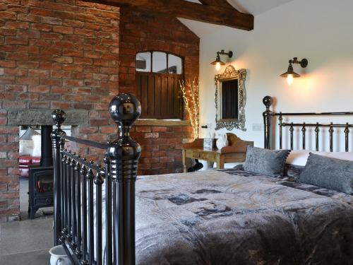a bedroom with a bed and a brick wall at Sunset Barn - Uk12855 in Normanby