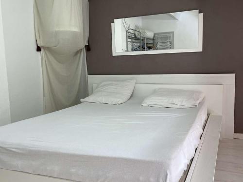un lit blanc avec deux oreillers dessus dans l'établissement Pavillon calme à Narbonne Plage, 6 couchages, grande terrasse, piscine et parking privé - FR-1-229B-67, à Narbonne