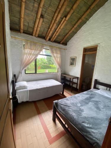 1 Schlafzimmer mit 2 Betten und einem Fenster in der Unterkunft Secretos del Carriel Finca Cafetera in Quimbaya