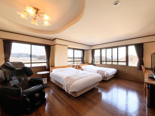 una habitación de hotel con 2 camas y una silla en Hotel Tsubakino en Yamanouchi