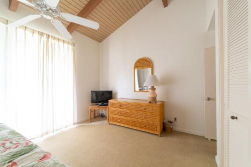 a bedroom with a bed and a dresser with a mirror at Anthurium Condo in Kahuku