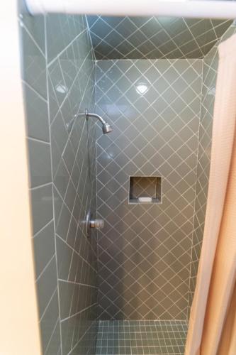 a bathroom with a shower with a tiled floor at Anthurium Condo in Kahuku