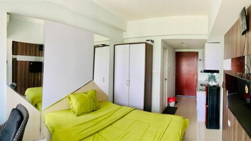 a bedroom with a bed with a yellow blanket at Apartemen Mahogany By Ruang Sultan in Karawang