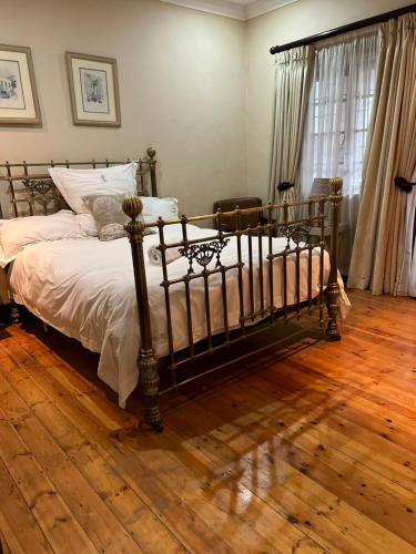 um quarto com uma cama e piso em madeira em FernIvy Guest House em Pretoria