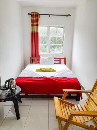 a bedroom with a red and white bed and a window at The Green View in Pattipola