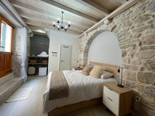 sypialnia z kamienną ścianą i dużym łóżkiem w obiekcie Knez apartments and rooms w mieście Kaštela